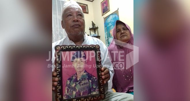 Orang tua Serda Rikson, Suwardi dan Armaneli saat memegang foto anaknya semalam (28/8). Jenazah Serda Rikson akan dikebumikan di Palembang