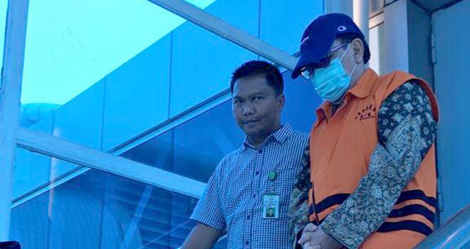 Tersangka kasus uang ketok palu, Asiang, di dampingi petugas dari Kejati Jambi, Doni, saat sampai di bandara STS Jambi