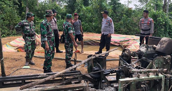 Petugas menutup sumur minyak illegal dan mengamankan barang bukti.


