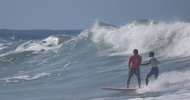Surfer Filipina Roger Casugay (kanan) membantu Arip Nurhidayat tali kekangnya lepas dan nyaris tergulung ombak. 
