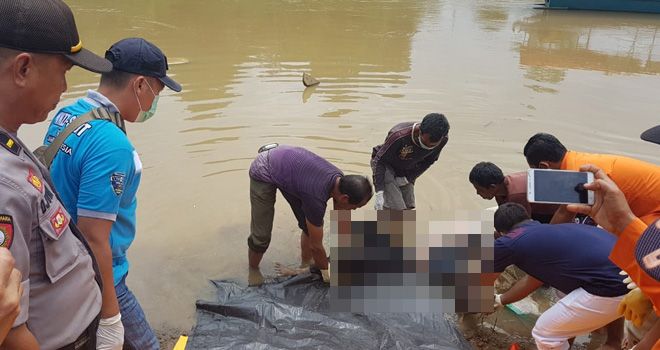 Petugas dibantu warga saat malakukan evakuasi terhadap jasad Waryono yang tenggelam di Sungai Batang Jujuhan sejak hari Sabtu (7/12) lalu.