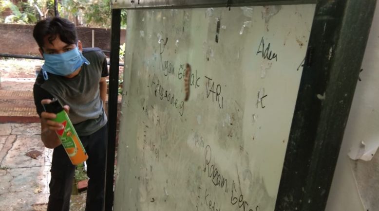 Penjaga sekolah menggunakan semprotan pembasmi serangga untuk menghalau serangan ulat bulu.