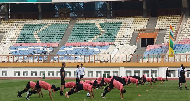 Timnas Indonesia U-19 yang sedang seleksi menjalani latihan dengan latar tribun timur penonton di Stadion Wibawa Mukti yang rusak. 
