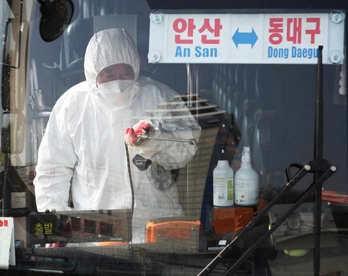 Seorang pekerja dari dinas kesehatan melakukan penyemprotan desinfektan di bus yang berangkat ke Daegu.
