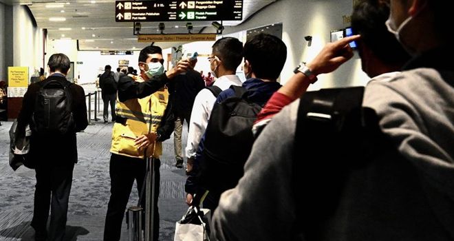Seorang petugas mengecek kondisi kesehatan penumpang saat mendarat di Bandara Soekarno-Hatta, Minggu (23/2).
