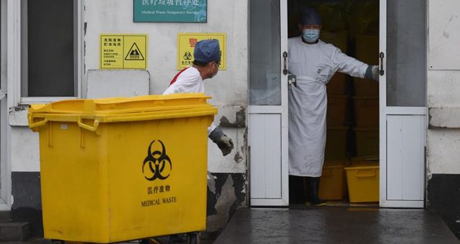 LIMBAH MEDIS: Seorang pekerja membawa gerobak penuh dengan limbah medis melewati kamar mayat, ke fasilitas penyimpanan di Rumah Sakit Youan di Beijing, kemarin. Rumah Sakit Youan salah satu dari dua puluh rumah sakit di Beijing yang merawat pasien virus corona. Enam petugas kesehatan telah meninggal akibat terinfeksi virus yang juga disebut Covid-19.
