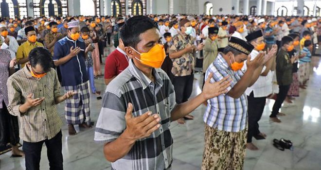 MEMOHON AMPUNAN: Dengan bermasker, jamaah menengadahkan kedua tangan. Mereka berdoa agar pandemi Covid-19 segera rampung. Tahun ini masjid tidak menggelar salat Idul Fitri.
