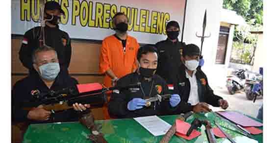 Tersangka Gusti Sudriyasa saat ditemui di Mapolres Buleleng, Senin (29/6) bersama sejumlah barang bukti berupa senjata tajam, senapan angin, dan pistol gas jenis organ.