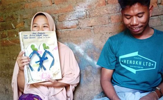 Helmi Susanti, memegang bingkai berisikan sandal jepit yang merupakan mahar pernikahannya dengan Iwan Firman Wahyudi. 