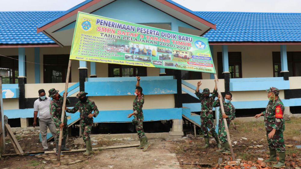 Satgas TMMD Bantu Perbaiki Pemasangan Banner Penerimaan Siswa/i Baru di SMPN Satu Atap 9 Desa Labuhan Pering