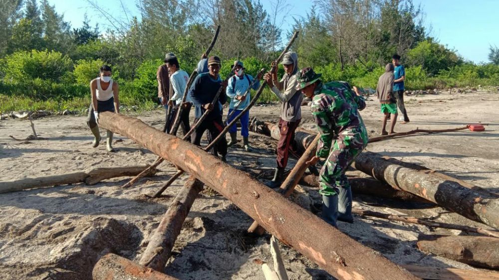 Satga TMMD Bersama Warga Desa Labuhan Pering Gotong royong Angkut Potongan Material yang Hanyut

