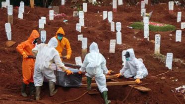 BAY ISMOYO / AFP PINDAHKAN MAYAT TERPAPAR COVID-19: Para pekerja memindahkan peti mati korban Covid-19 ke sebuah pemakaman di Jakarta, kemarin.