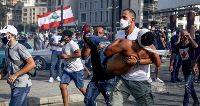 FOTO: PATRICK BAZ / AFP AKSI MASSA: Bintang bola basket Lebanon Fadi al-Khatib membawa seorang demonstran yang terluka menjauh dari bentrokan di pusat Kota Beirut, kemarin. Ini menyusul demonstrasi menentang kepemimpinan politik yang mereka tuduh atas ledakan monster yang menewaskan lebih dari 150 orang dan merusak ibu kota Beirut.