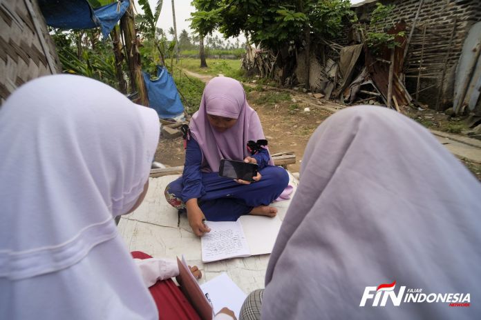 Tiga siswi melakukan belajar bersama di depan halaman rumah