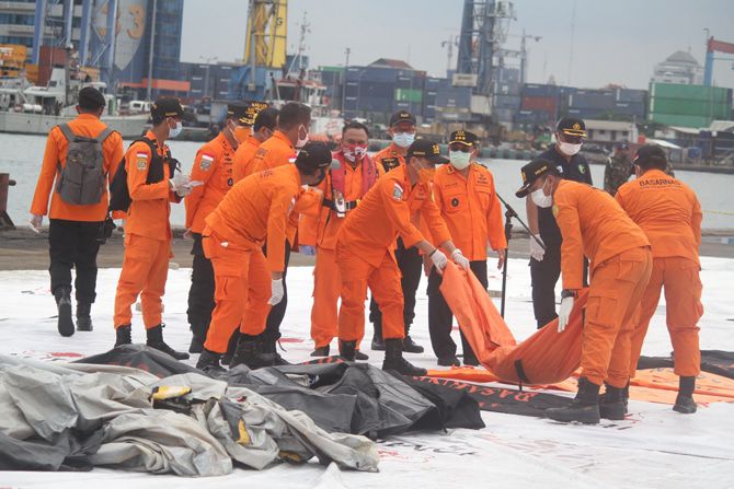 Petugas membawa kantung jenazah korban pesawat Sriwijaya Air SJ182 rute Jakarta - Pontianak di Dermaga JICT, Tanjung Priok, Jakarta, Minggu (10/1/2021).