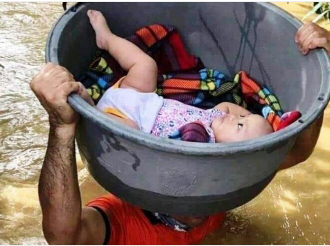 Seorang pria menyelamatkan bayi dengan menggunakan baskom saat banjir besar terjadi. (IST)
