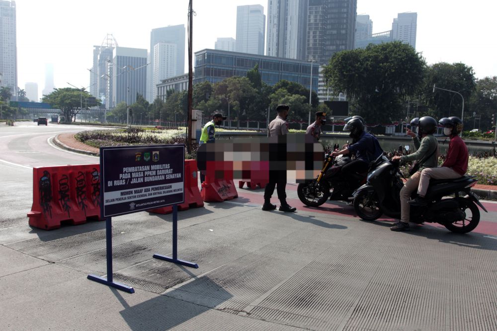 Anggota Kepolisi memberhentikan pengendara yang ingin melintas jalan Sudirman saat berlangsungnya Pemberlakuan Pembatasan Kegiatan Masyarakat (PPKM) Darurat di kawasan Bundaran Senayan, Jakarta, Sabtu (3/7). Mulai hari ini pemerintah melakukan PPKM Darurat di sejumlah daerah sebagai upaya memutus rantai penyebaran Covid-19 yang terus meningkat. 
