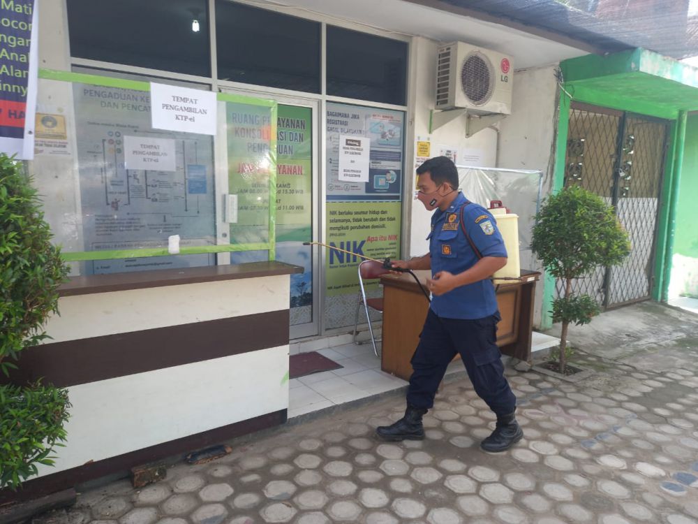 TUTUP : Masyarakat yang datang ke Disdukcapil terpaksa putar balik. (inzet) Kantor Disdukcapil Kota Jambi dilakukan sterilasi dengan penyemprotan disinfektan.