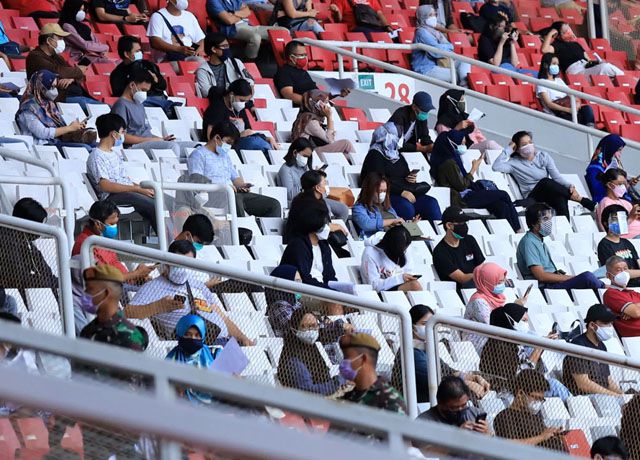 Masyarakat mengantre untuk melakukan vaksinasi Covid-19 massal di Stadion Utama Gelora Bung Karno, Senayan, Jakarta, Senin (5/07). Pemprov DKI Jakarta menggelar program Serbuan Vaksin Massal yang diperuntukan bagi warga minimal berusia 12 tahun guna mendukung program pemerintah pusat satu hari satu juta vaksinasi untuk menuju Indonesia sehat bebas COVID-19. 