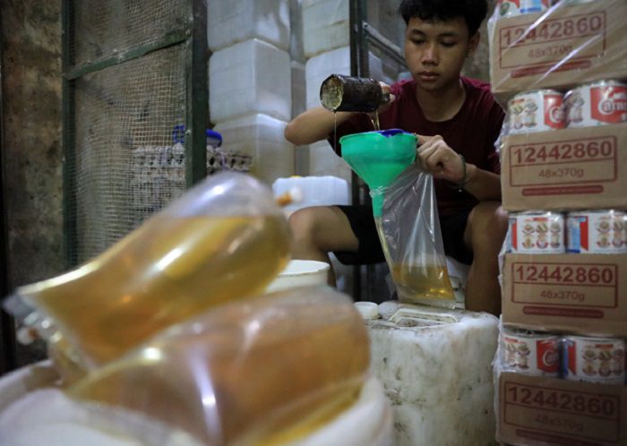 Pekerja menuang minyak curah di salah satu agen sembako di kawasan pasar Pondok Labu, Jakarta, Rabu (26/1/2022). Setelah pemerintah membelakukan kebijakan satu harga, yakni minyak goreng berbanderol Rp 14 ribu per liter, ternyata penyesuaian harga tersebut belum terjadi di semua pasar tradisional. Salah satunya di Pasar Jaya Pondok Labu, Jakarta.