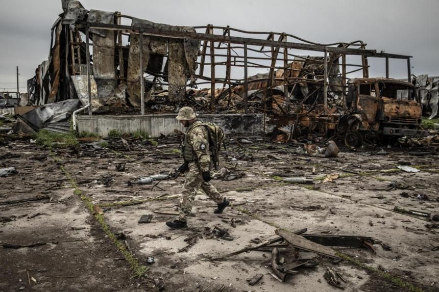 Seorang tentara Ukraina berjalan melewati gudang yang hancur tempat pasukan Rusia bermarkas di Tsyrkuny pada Minggu 15 Mei 2022.