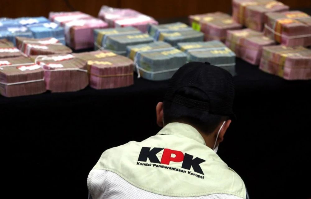 Penyidik KPK di depan uang barang bukti kasus suap. 
