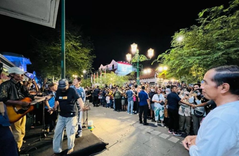Presiden Joko Widodo (kanan) menikmati denyut kehidupan masyarakat pada malam hari di Yogyakarta, termasuk nyanyian dari para seniman musik jalanan Malioboro, Daerah Istimewa Yogyakarta, Sabtu (16/10).