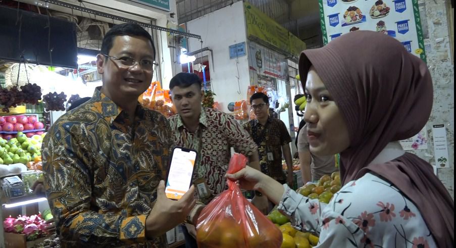 SEVP Digital Banking Saut Parulian Saragih (kiri) menggunakan BSI Mobile untuk transaksi QRIS di salah satu kios buah di Pasar Gede Solo, Surakarta, Senin (15/01).